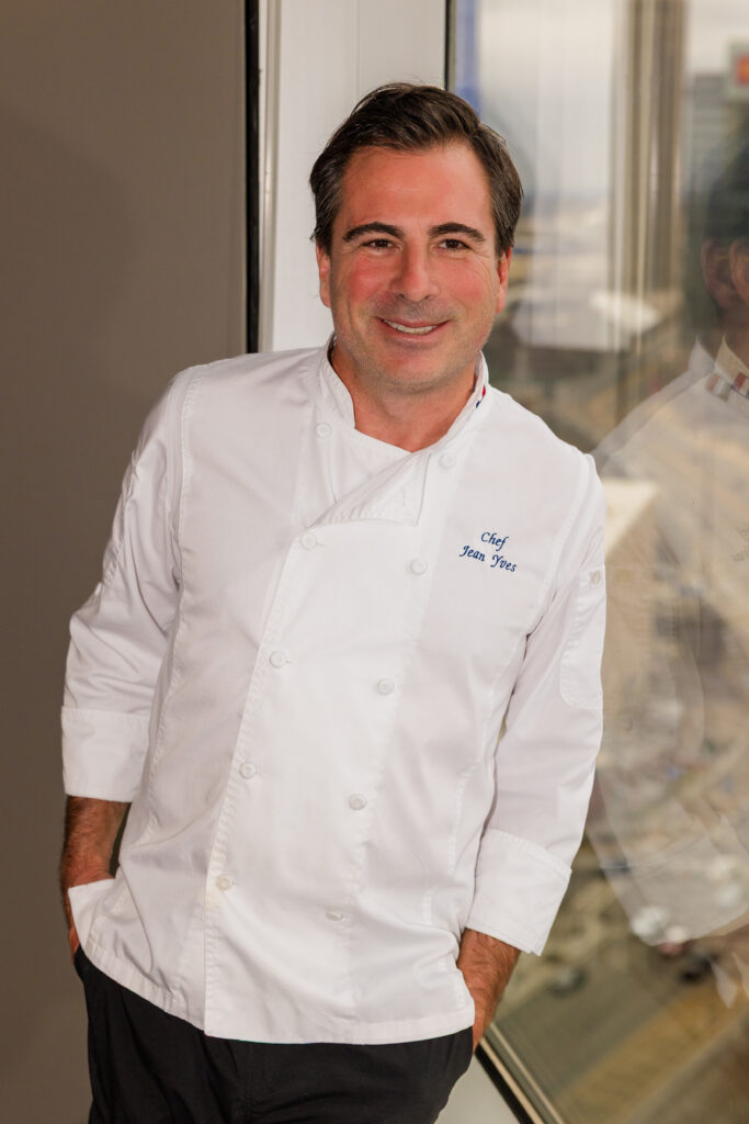 Professional chef headshot leaning against window with hands in pockets in natural light
