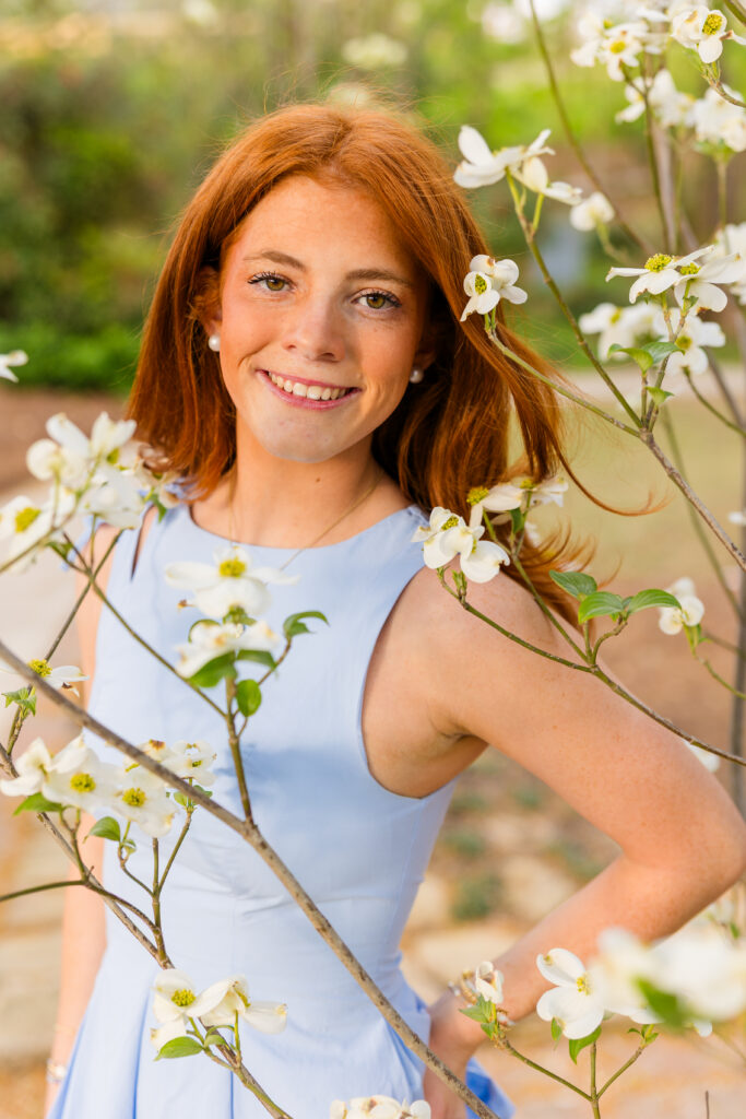 Senior girl posing in front of blooming white flowers tree in Atlanta spring