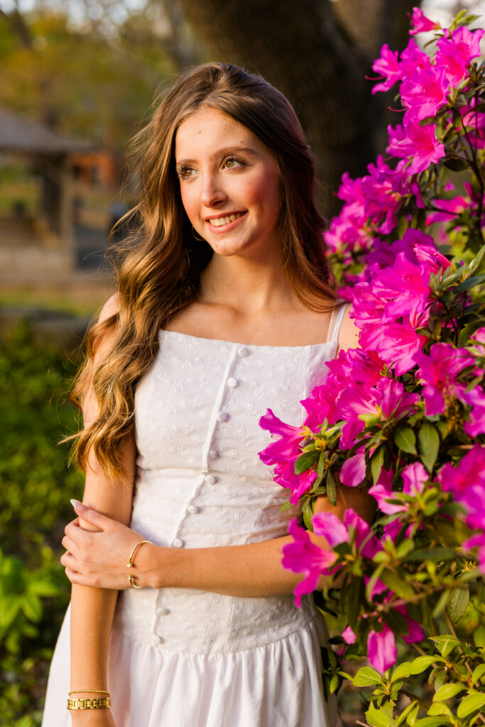Senior posing in front of pink azalea flowers in Piedmont Park