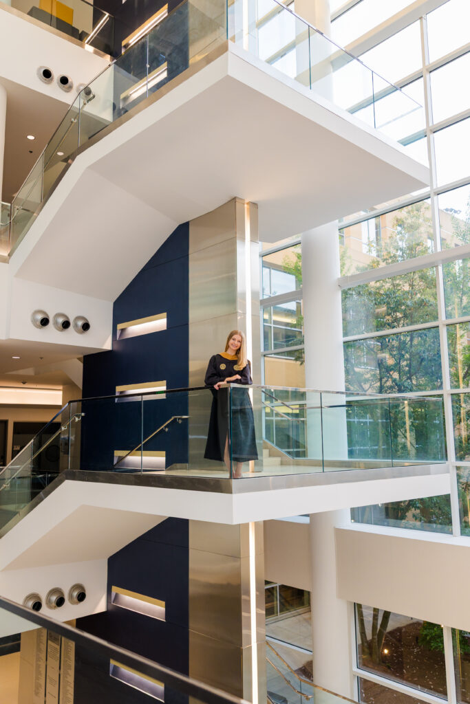 Wide architectural graduation portrait of Gabriela on the modern staircase at Scheller