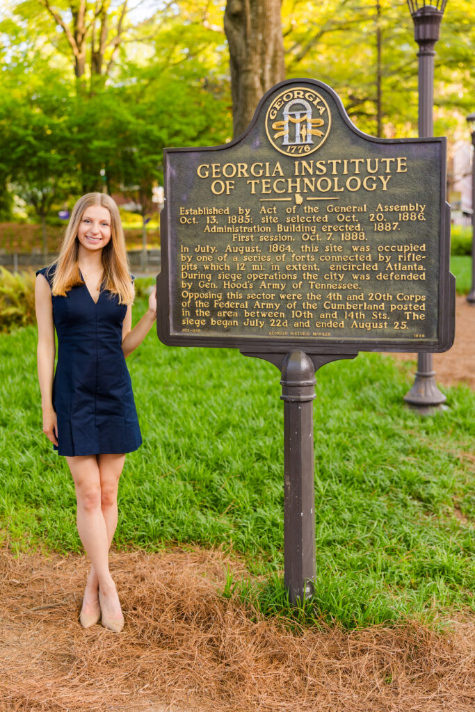 Gabriela posing in a blue dress at the Georgia Tech sign during graduation session